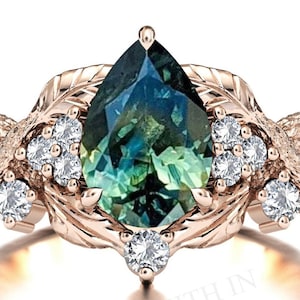 Può includere: Un anello in oro rosa con una pietra preziosa verde e blu a forma di pera, decorato con un motivo a foglie e piccole pietre preziose trasparenti.