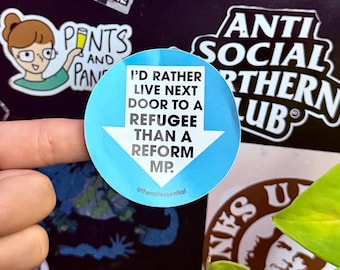 May include: A round, light blue sticker with the text "I'D RATHER LIVE NEXT DOOR TO A REFUGEE THAN A REFORM MP." in white. The sticker has a white arrow pointing down. Other stickers and a hand are in the background.