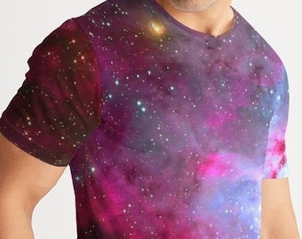 May include: A man wearing a short-sleeved t-shirt with a galaxy print. The shirt features a pink, blue, and purple nebula with white stars.