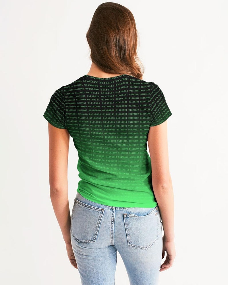 Op de afbeelding: Een zwart en groen T-shirt met een verloopontwerp met een herhalend patroon van binaire code. De code is groen op een zwarte achtergrond.