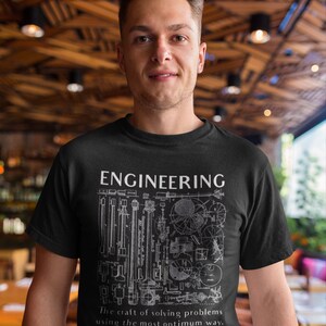 May include: A black t-shirt featuring a white graphic design of various engineering drawings and the text "ENGINEERING The craft of solving problems using the most optimum way."
