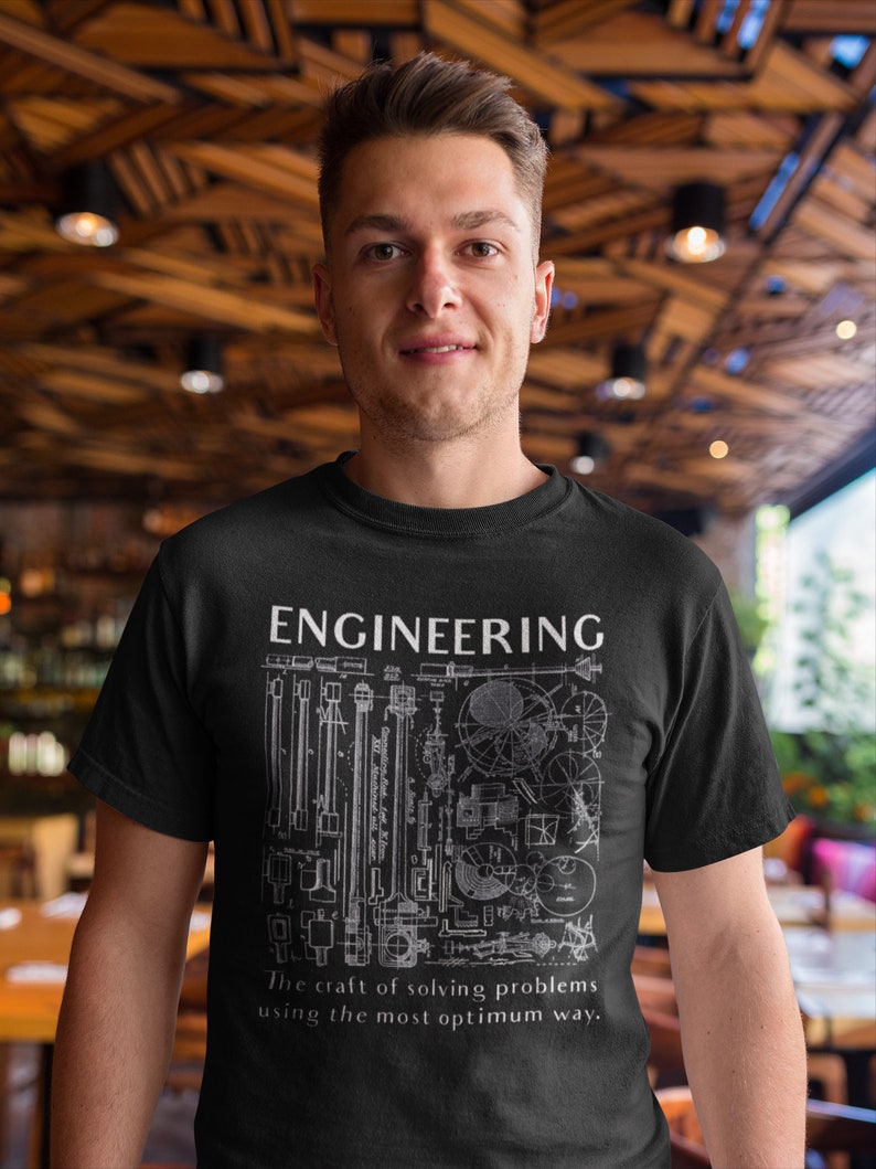 May include: A black t-shirt featuring a white graphic design of various engineering drawings and the text "ENGINEERING The craft of solving problems using the most optimum way."