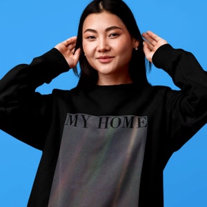 Puede incluir: Sudadera negra con un estampado gr&aacute;fico de una galaxia y el texto "MY HOME" en blanco.