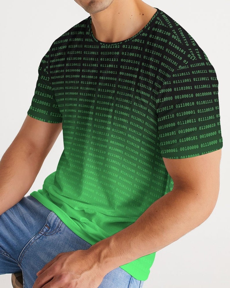 Op de afbeelding: Een zwart en groen T-shirt met korte mouwen met een verloop van binaire code. De code is groen en vervaagt naar zwart aan de bovenkant van het shirt.