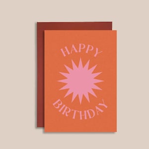 May include: Orange card with a pink starburst design and the text "Happy Birthday" in pink.