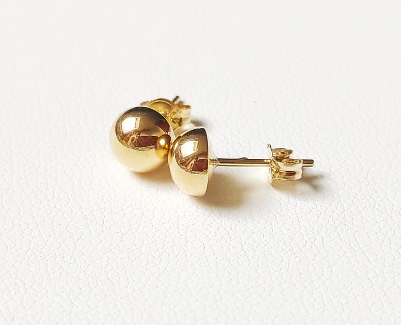Pu&ograve; includere: Un paio di orecchini a lobo in oro con sfere. Gli orecchini sono semplici ed eleganti e sarebbero un ottimo regalo per ogni occasione.