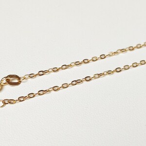 May include: A gold chain necklace with a lobster clasp closure. The chain is made of small, oval-shaped links.