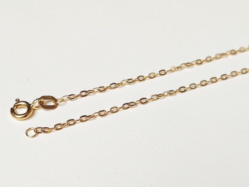 May include: A gold chain necklace with a lobster clasp closure. The chain is made of small, oval-shaped links.