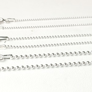May include: Four silver ball chain necklaces of varying lengths, displayed on a white surface.