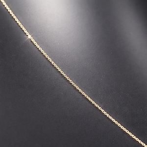 Puede incluir: Un delicado collar de cadena dorada sobre un fondo oscuro. La cadena est&aacute; compuesta por peque&ntilde;os eslabones espaciados uniformemente, creando un dise&ntilde;o sutil y elegante. El color dorado refleja la luz, a&ntilde;adiendo un toque de brillo.