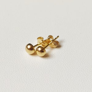 Pu&ograve; includere: Un paio di orecchini a bottone in oro con un design rotondo.