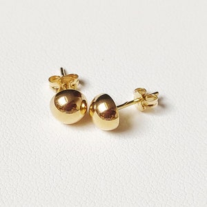 Pu&ograve; includere: Un paio di orecchini a lobo in oro con sfere. Gli orecchini sono semplici ed eleganti e sarebbero un ottimo regalo per ogni occasione.