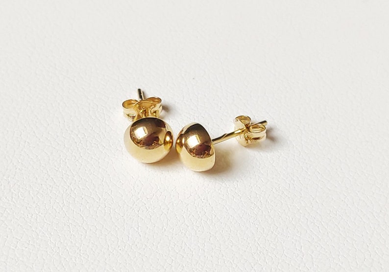 Pu&ograve; includere: Un paio di orecchini a lobo in oro con sfere. Gli orecchini sono semplici ed eleganti e sarebbero un ottimo regalo per ogni occasione.