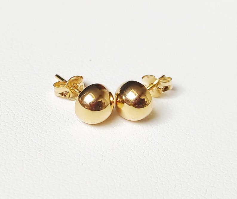Pu&ograve; includere: Un paio di orecchini a lobo in oro con sfere. Gli orecchini sono semplici ed eleganti e sarebbero un ottimo regalo per ogni occasione.