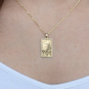 Puede incluir: Un collar de cadena de oro con un colgante rectangular que presenta un diseño grabado detallado.