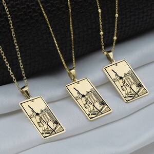 Puede incluir: Cuatro collares de oro con colgantes rectangulares que representan imágenes de cartas de tarot. Los colgantes representan la carta Tres de Espadas del Tarot Mayor.
