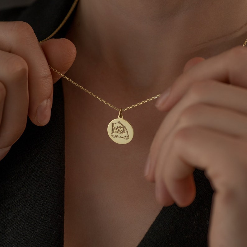May include: A gold chain necklace with a round pendant featuring an engraved image of a dog.