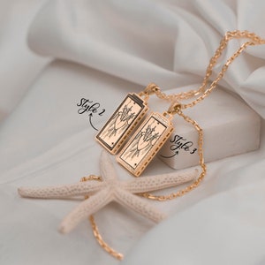 Puede incluir: Dos colgantes de oro con una imagen en blanco y negro de un coraz&oacute;n atravesado por espadas. Los colgantes est&aacute;n en una cadena de oro y est&aacute;n etiquetados como "Style 2" y "Style 3".