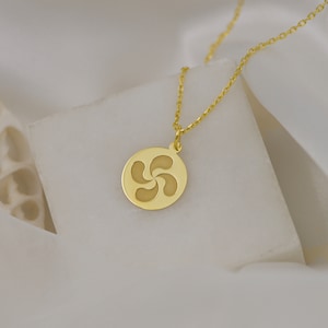 May include: A gold necklace with a round pendant featuring a stylized four-pointed star design.