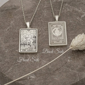 May include: A silver necklace with a pendant featuring the The Star tarot card on the front and a decorative design on the back.