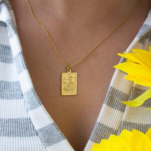 Op de afbeelding: Gouden ketting met een rechthoekige hanger met een skelet dat een zeis vasthoudt en de woorden "Death The Knave".
