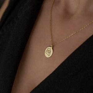 May include: A gold chain necklace with a round pendant featuring an engraved image of a dog.