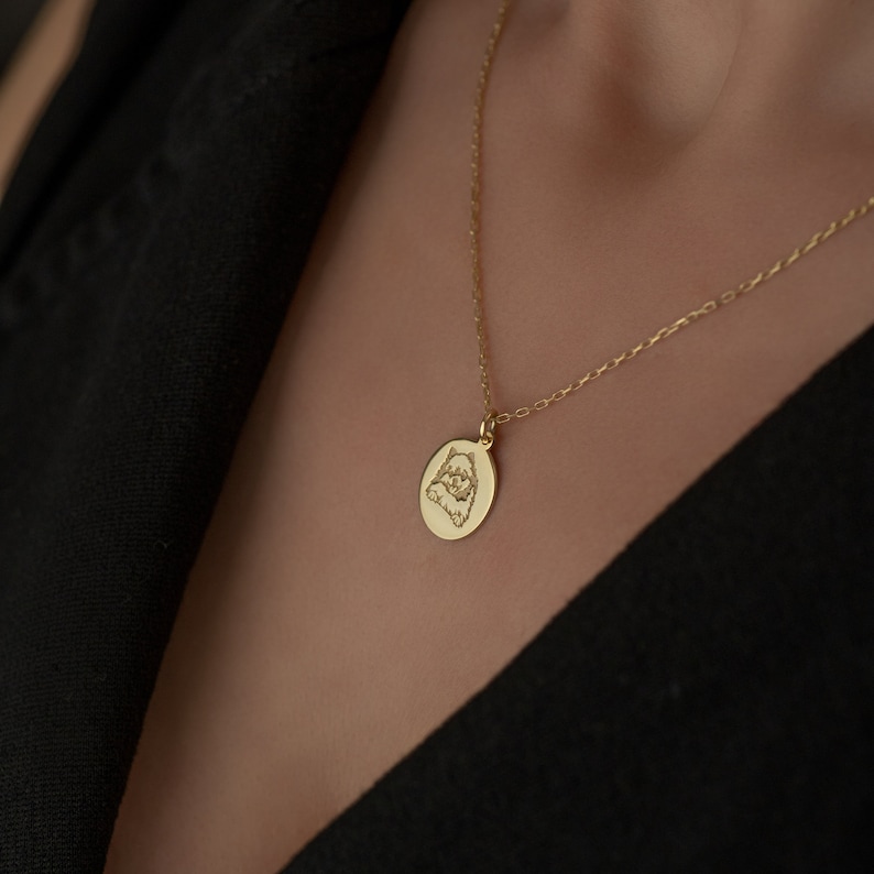 May include: A gold chain necklace with a round pendant featuring an engraved image of a dog.