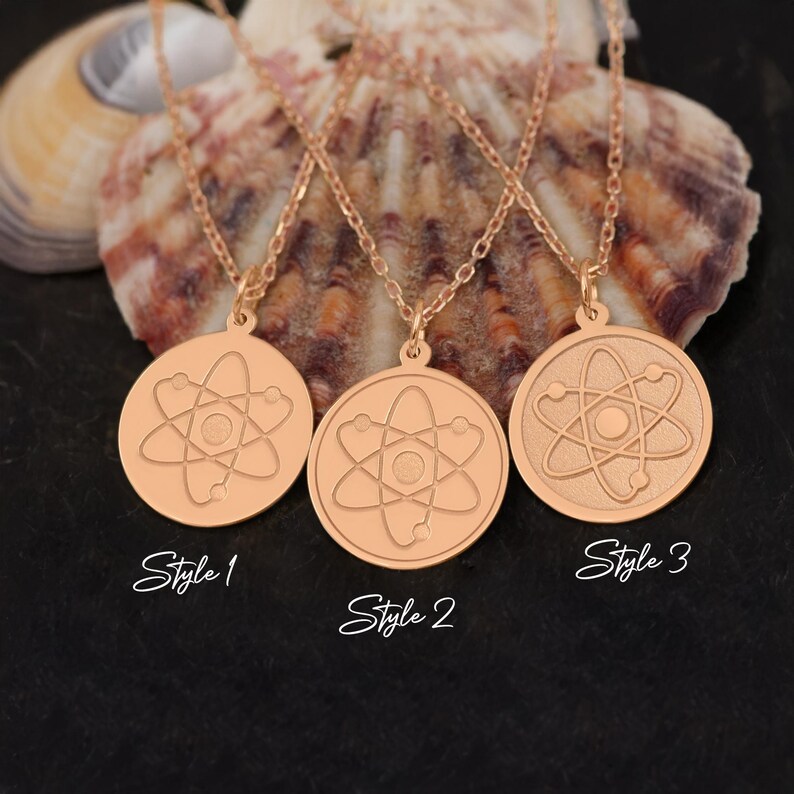 May include: Three gold necklaces with atom pendant charms. The pendants are round and feature a stylized atom design. The necklaces are labeled "Style 1", "Style 2", and "Style 3".