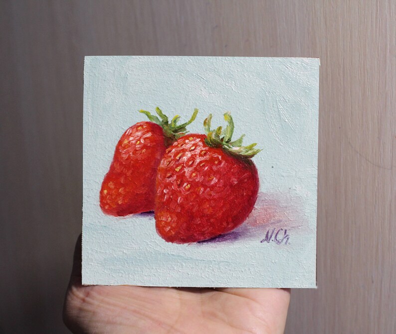 Two red strawberries painted on a light blue canvas. The strawberries are in focus and the background is blurred. The painting is signed .