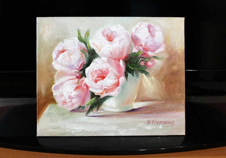 Peonies oil painting of a bouquet of pink peonies in a white vase. The flowers have multiple layers of petals and green leaves. The background is a soft, neutral color, and the painting is signed in the bottom right corner. The painting is signed "N. Chernous" in the bottom right corner.