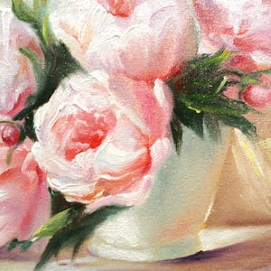 Peonies oil painting of a bouquet of pink peonies in a white vase. The flowers have multiple layers of petals and green leaves. The background is a soft, neutral color, and the painting is signed in the bottom right corner.