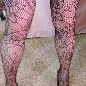 Peut inclure: Collants en résille noirs avec un motif en toile d'araignée. Les collants sont portés avec des chaussures noires à talons hauts.