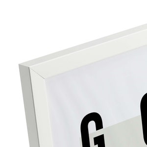 May include: White picture frame with a black and white print of the word "GOOD" inside. The frame has a simple, modern design.