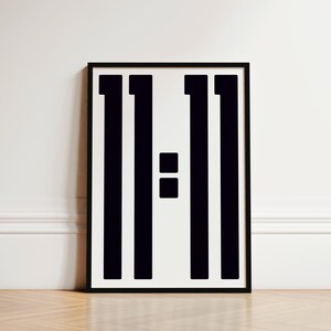 May include: Black and white print of the number 11:11 in a minimalist style. The print is framed in a black frame.