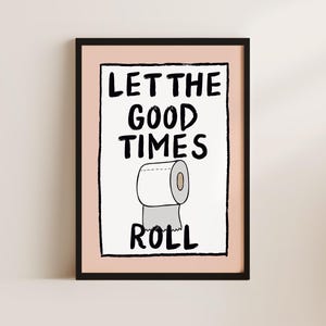 May include: A black framed print with a pink background. The print features a hand-drawn illustration of a toilet paper roll with the text "Let the good times roll".