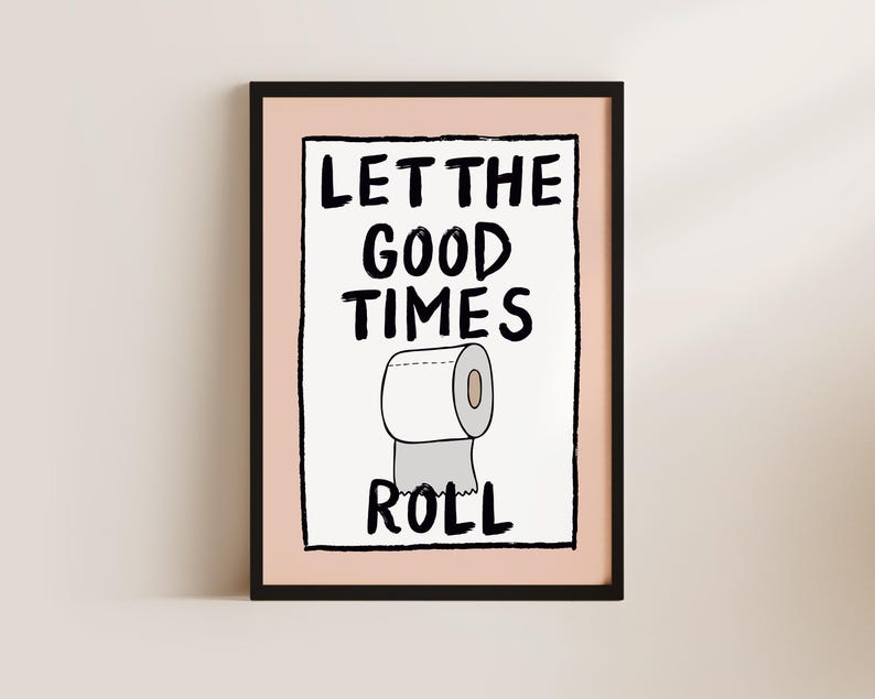 May include: A black framed print with a pink background. The print features a hand-drawn illustration of a toilet paper roll with the text "Let the good times roll".