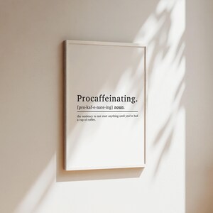 May include: A white framed print with the word "Procaffeinating" defined as "the tendency to not start anything until you've had a cup of coffee".