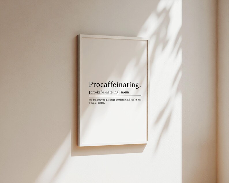 May include: A white framed print with the word "Procaffeinating" defined as "the tendency to not start anything until you've had a cup of coffee".