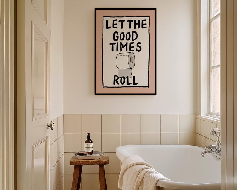 May include: A bathroom with a white bathtub, a wooden stool, and a framed print on the wall that says "Let the good times roll" with a cartoon image of a toilet paper roll.