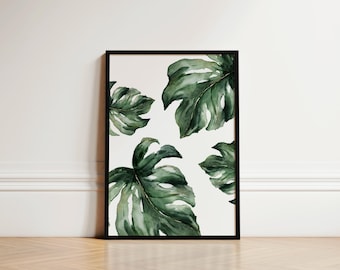 May include: A framed print featuring a watercolour painting of green tropical leaves on a white background.