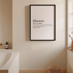 May include: A black framed print with the word "Shower" in a white sans-serif font. The definition of the word is below, "a tranquil place where the mind is free to wander and savour all of life's treasures, singing may occur."