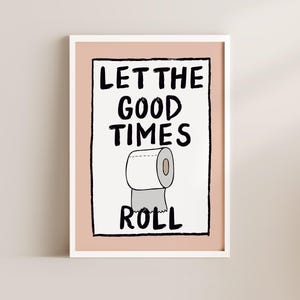 May include: A white framed print with a pink background and black text that reads "Let the good times roll". A cartoon drawing of a roll of toilet paper is below the text.