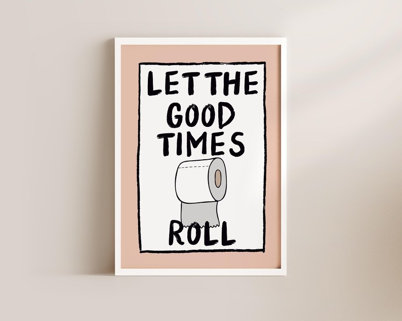 May include: A white framed print with a pink background and black text that reads "Let the good times roll". A cartoon drawing of a roll of toilet paper is below the text.