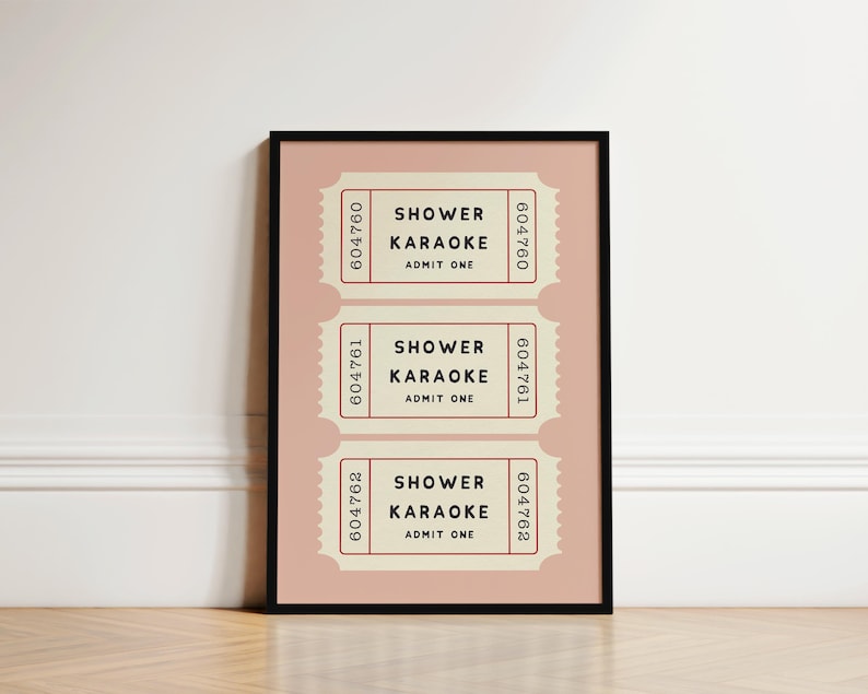 May include: A framed print featuring three vintage-style tickets. Each ticket, in a cream color with a pink background, reads "SHOWER KARAOKE ADMIT ONE." The tickets have a serrated edge and a serial number. The frame is black.