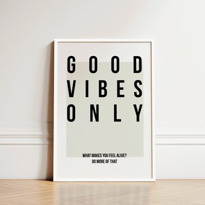 May include: A white framed print with the text "GOOD VIBES ONLY" in black letters. The print also includes the text "WHAT MAKES YOU FEEL ALIVE? DO MORE OF THAT."