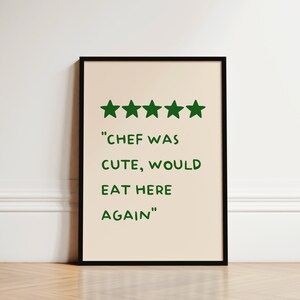 May include: A black framed print with a beige background. Five green stars are displayed at the top of the print. The text "CHEF WAS CUTE, WOULD EAT HERE AGAIN" is written in green below the stars.
