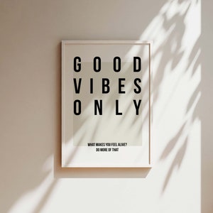 May include: A white framed print with the text "GOOD VIBES ONLY" in black letters. The print also includes the text "WHAT MAKES YOU FEEL ALIVE? DO MORE OF THAT."