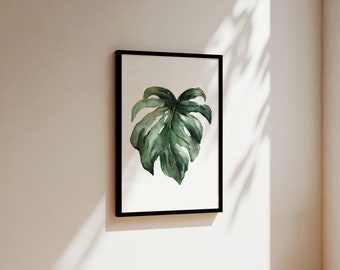 May include: A framed watercolour painting of a single green monstera leaf on a white background.