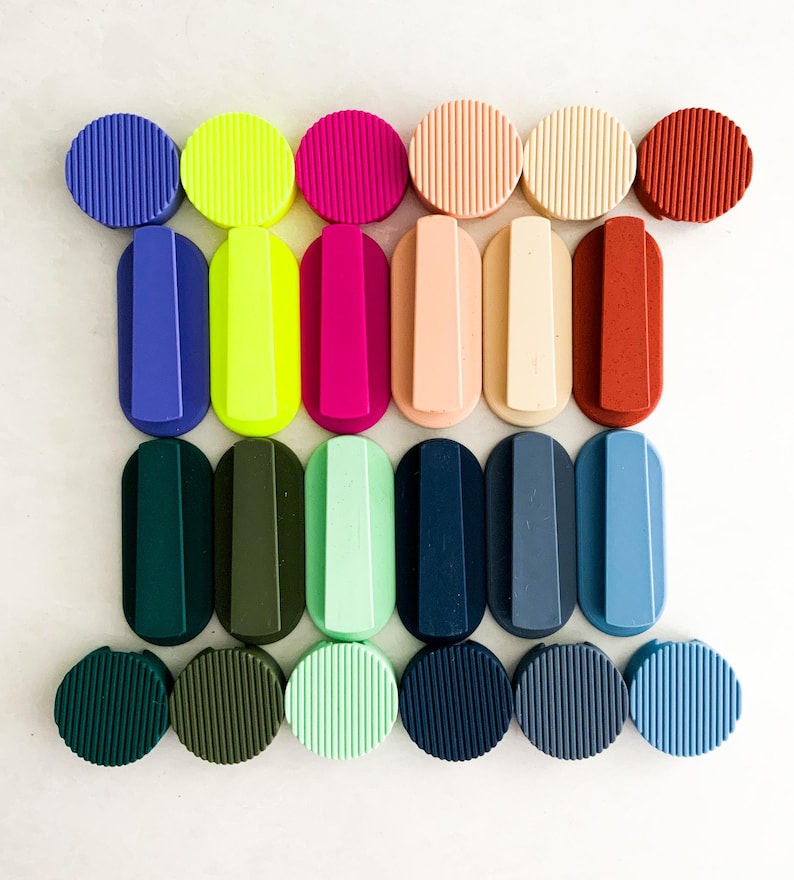 May include: A selection of colourful bottle stoppers and handles in shades of blue, green, pink, and neutral tones. The stoppers are round, while the handles are oval, all with a ribbed design. A vibrant and stylish assortment.