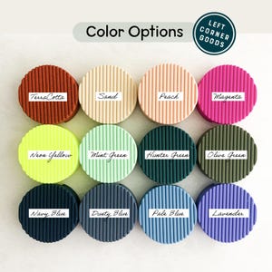 May include: Twelve circular, ribbed items in a range of colours: Terra Cotta, Sand, Peach, Magenta, Neon Yellow, Mint Green, Hunter Green, Olive Green, Navy Blue, Dusty Blue, Pale Blue, and Lavender. Each has a white label with its colour name. The text "Color Options" is at the top.